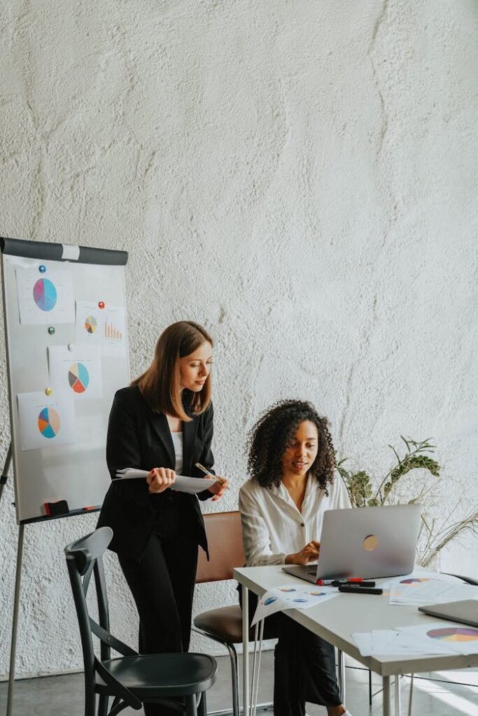 Mastering the First Impression: Your intriguing post title goes here Two businesswomen analyzing graphs on a whiteboard during a meeting.